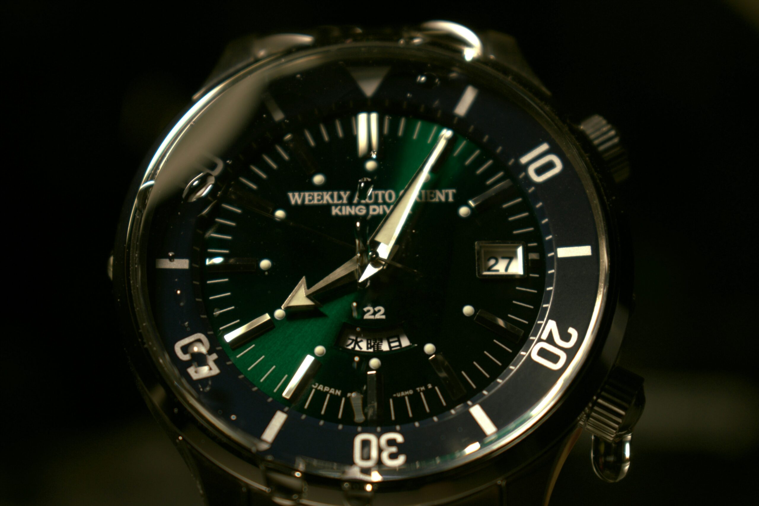 Close-up shot of a sleek navy blue dial watch with roman numerals under soft lighting.