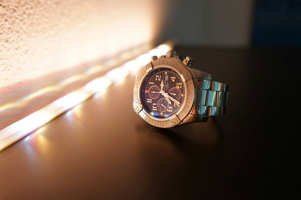 A sparkling watch on a velvet surface next to festive ornaments