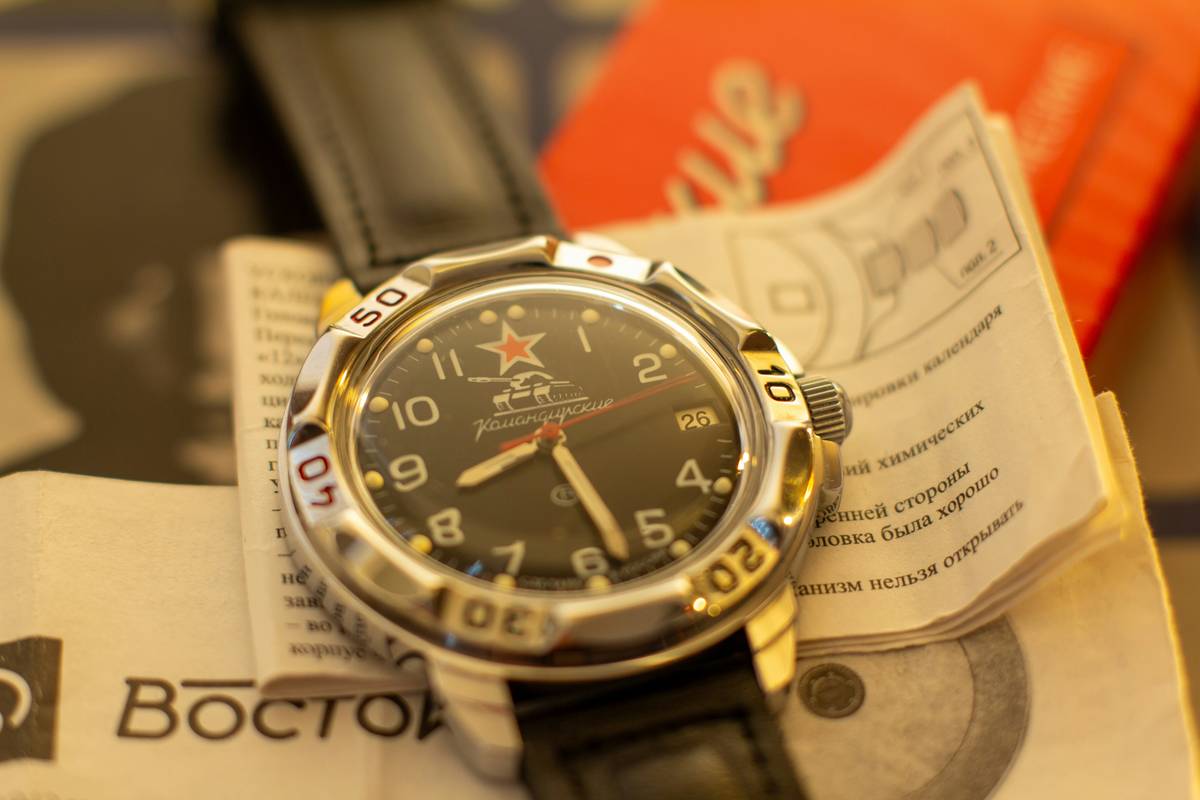 A close-up shot of a modified Rolex Submariner with custom shark fin-shaped markers glowing vividly in darkness.